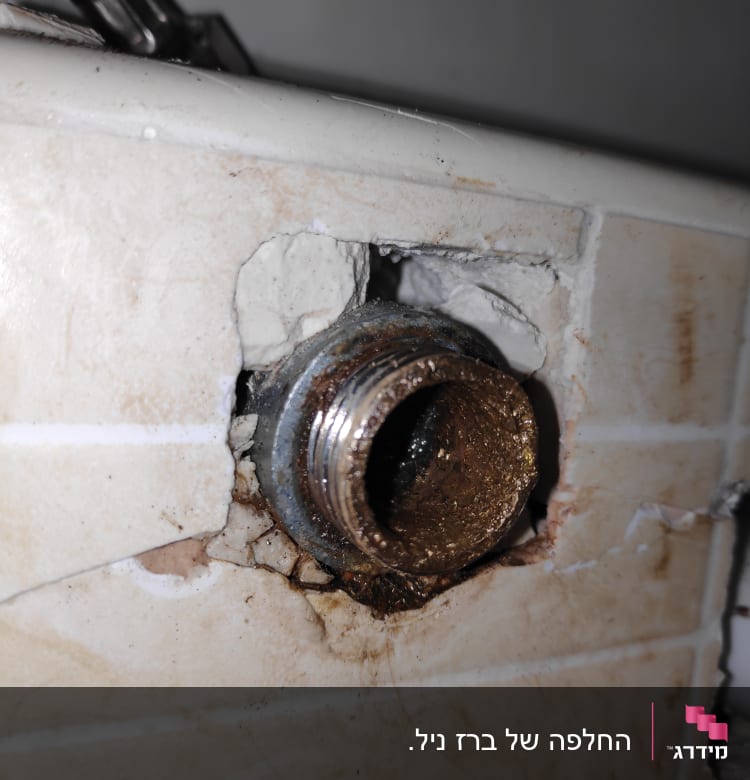 צינור מתכת חלוד בקיר עם חיבור שבור